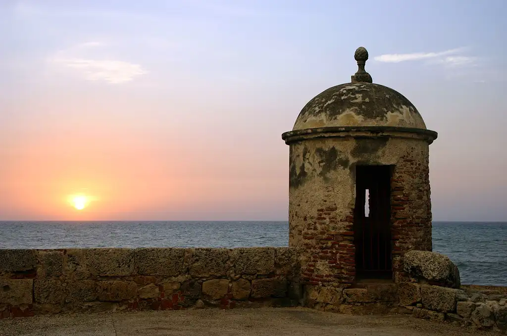 Centro histórico colonial rodeado de murallas frente al mar Caribe, con calles coloridas y balcones llenos de flores.
